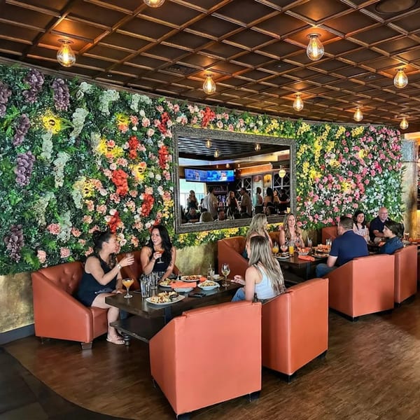 Diners enjoying food and drinks in Anejo Cantina and Grill, with a floral wall and mirror.